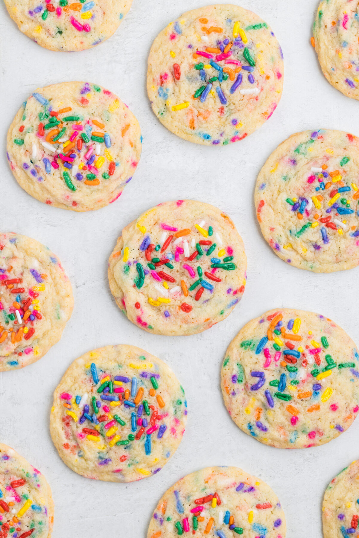 Funfetti cookies laid flat on a white background about 12 cookies.